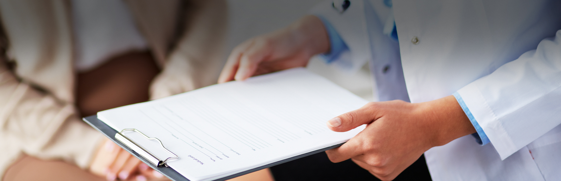 Close up of medical professional holding clipboard with patient forms